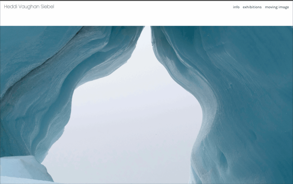 Ice cave opening, viewed from below; blue-tinged ice walls curve upward against a hazy sky